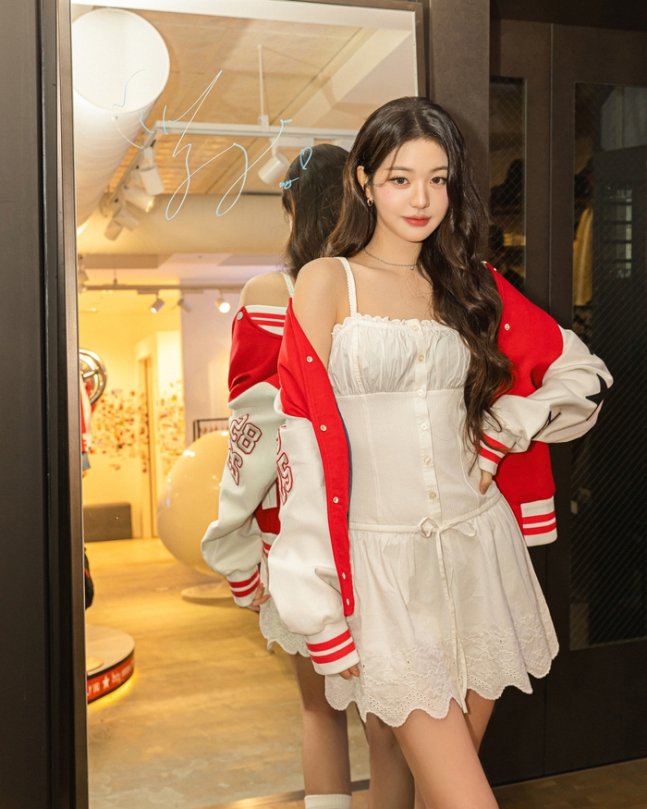 Jang Wonyoung en robe blanche œillets et veste varsity Tommy Girl à Tokyo